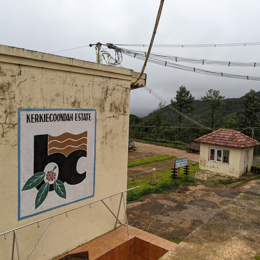 Kerkiecoondah Estate sign on a building with a view of a small house and mountains in the background.