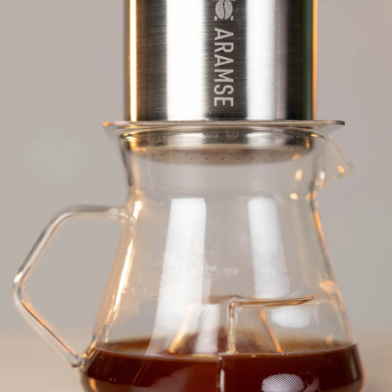 Coffee maker with glass carafe and metal top on a blurred background