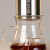 Coffee maker with glass carafe and metal top on a blurred background