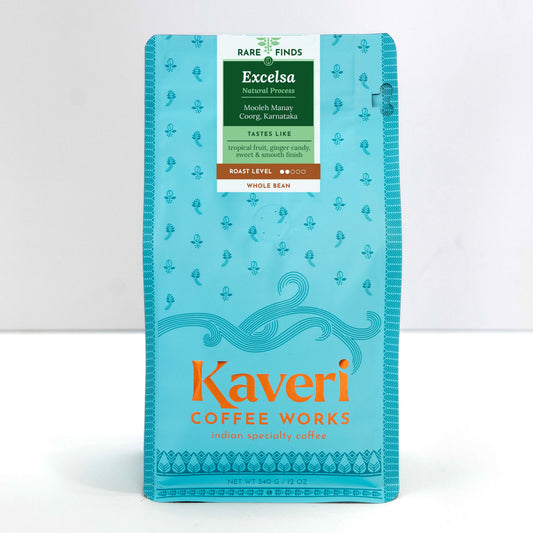 A package of Kaveri Coffee Works Excelsa whole bean coffee in a light blue-green stand-up pouch with a white and green label at the top, photographed against a clean white background.