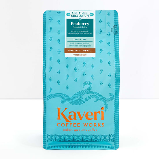 A package of Kaveri Coffee Works Peaberry whole bean coffee, featuring a bright turquoise blue bag with orange and white text and decorative patterns.