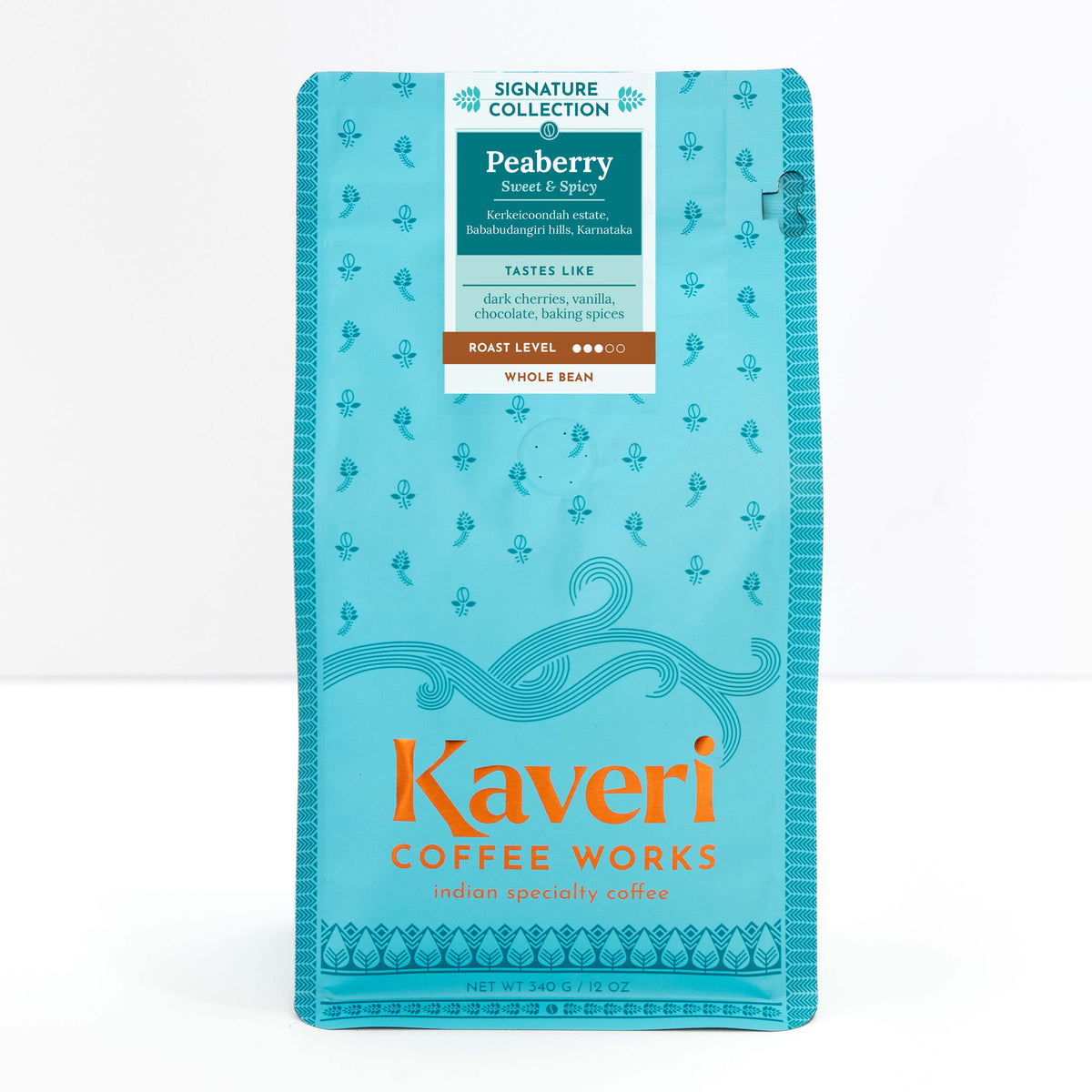A package of Kaveri Coffee Works Peaberry whole bean coffee, featuring a bright turquoise blue bag with orange and white text and decorative patterns.