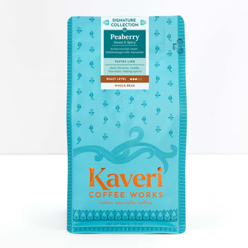 A package of Kaveri Coffee Works Peaberry whole bean coffee, featuring a bright turquoise blue bag with orange and white text and decorative patterns.
