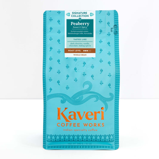 A package of Kaveri Coffee Works Peaberry whole bean coffee, featuring a bright turquoise blue bag with orange and white text and decorative patterns.
